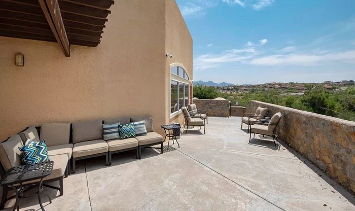 Charming outdoor patio with stylish seating, perfect for relaxation, offering stunning views of lush landscapes and distant mountains.