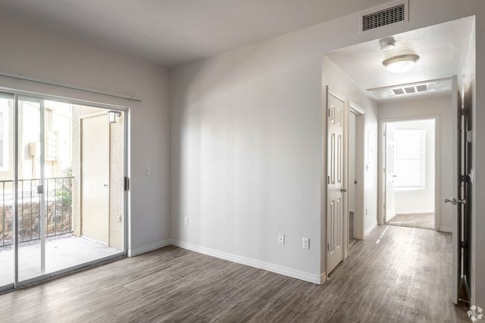 Bright and airy apartment hallway with modern wood flooring, leading to open patio doors and a sunlight-filled room.