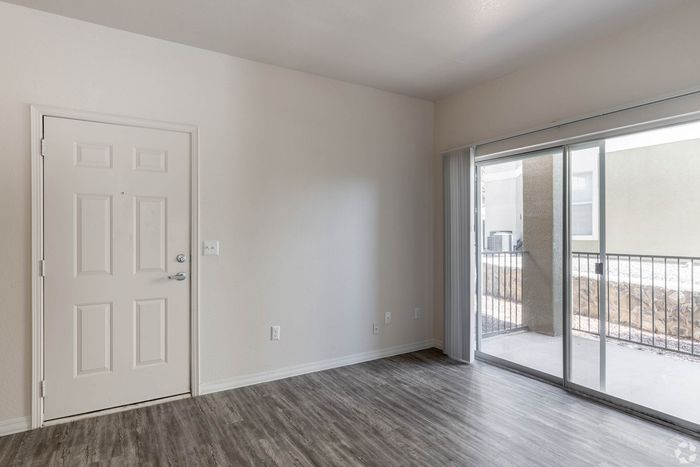 Bright and inviting interior with sleek wood flooring, large sliding glass doors for ample natural light, and a welcoming entrance.