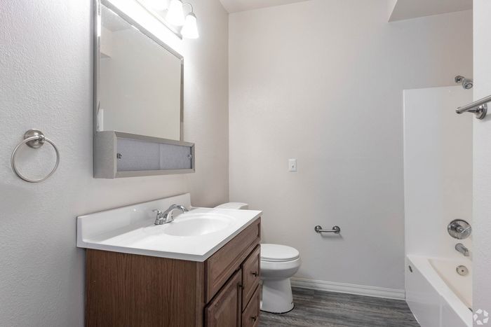 Modern bathroom featuring sleek fixtures, elegant vanity with ample storage, and a pristine tub-shower combination.