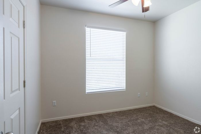 Bright and airy empty room with plush carpet and a window with blinds, perfect for a cozy retreat or creative space.