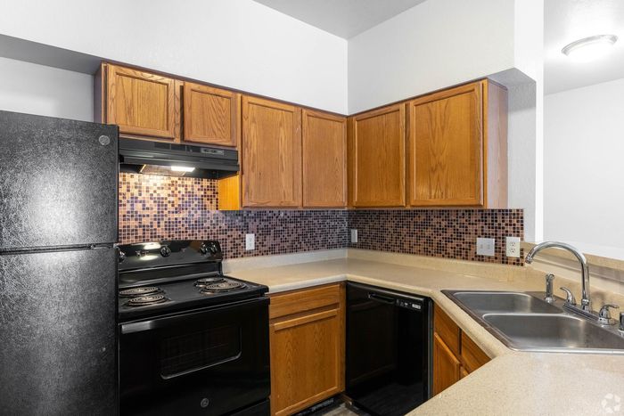 Chic kitchen featuring sleek black appliances, modern mosaic backsplash, and warm wood cabinetry for a cozy yet contemporary feel.