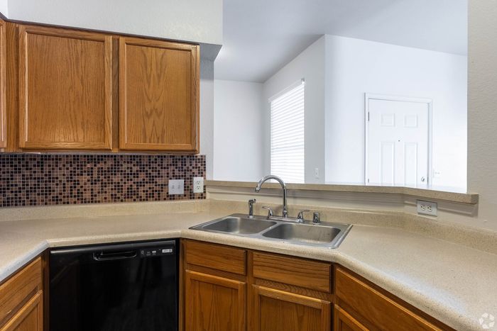 Modern kitchen with elegant tiled backsplash, dual sinks, and warm wooden cabinetry creating a cozy ambiance.