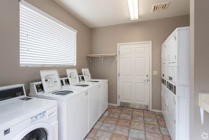 Bright and welcoming laundry room with modern washers and dryers, featuring ample natural light and convenient shelving.