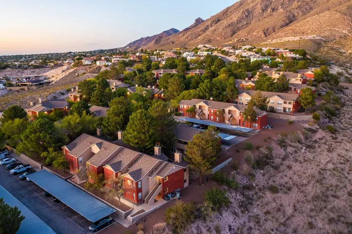 Scenic aerial view of charming apartments nestled in a lush, mountainous landscape, showcasing serene living with natural beauty.