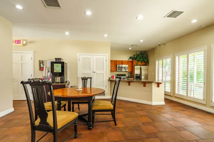 Inviting kitchen and dining area with elegant wooden table, cozy chairs, and bright natural light streaming through large windows.
