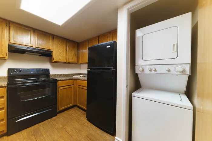 Cozy kitchen with elegant wooden cabinetry and modern appliances, featuring an in-unit stacked washer and dryer for convenience.