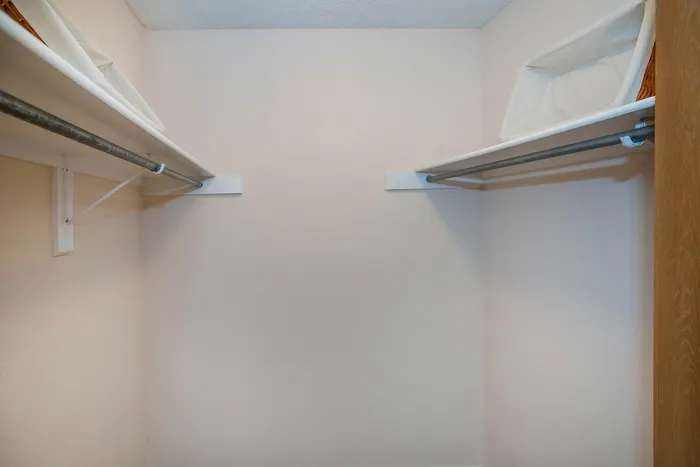 Spacious walk-in closet with dual hanging racks and upper storage shelves.