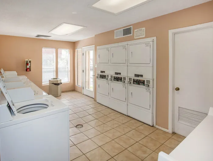 Bright and clean laundry room featuring modern washing machines and dryers, perfect for stress-free laundry days.