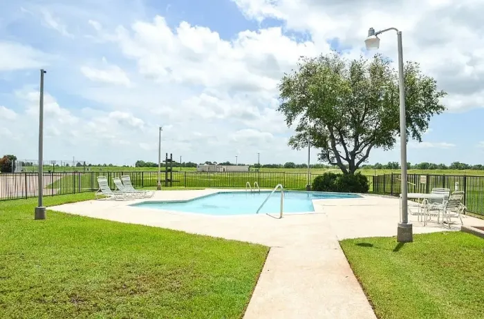 blue pool surrounded by grass and trees