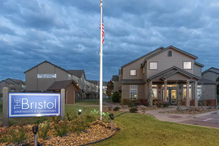Inviting entrance to The Bristol Apartments & Townhomes with beautifully manicured landscaping and a charming exterior. Now leasing for your dream home experience.