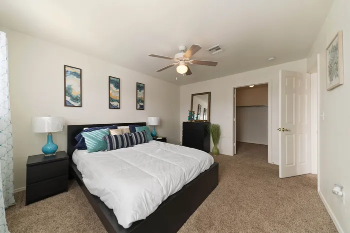 Inviting bedroom with plush carpet, stylish artwork, and elegant decor exuding modern comfort.
