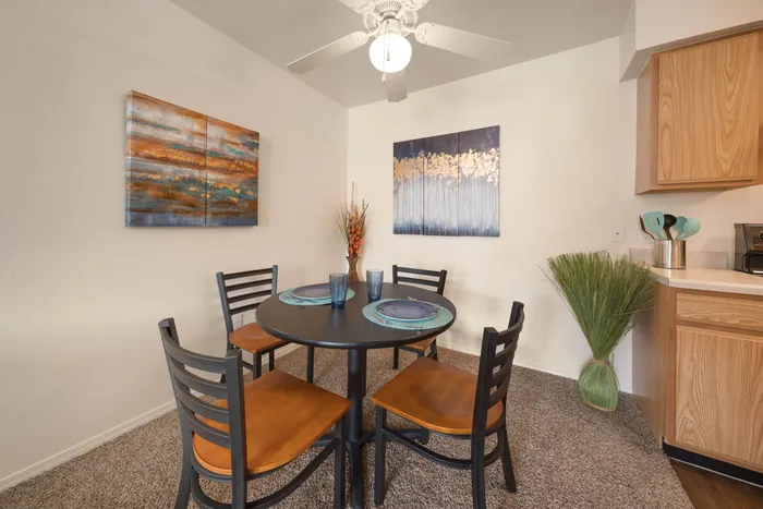 Charming dining area featuring a round table with elegant tableware, surrounded by modern art and natural accents, offering a cozy and inviting atmosphere.