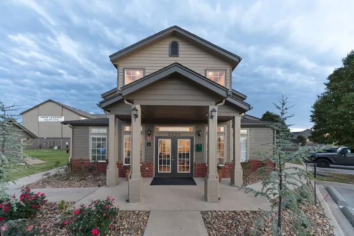 Inviting two-story apartment building with charming front porch, attractive landscaping, and ample parking, perfect for new tenants.