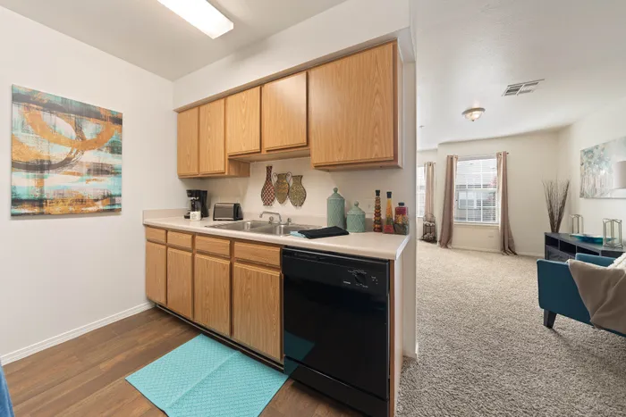 Inviting kitchen with modern wooden cabinetry, sleek countertops, and a view into a cozy, sunlit living room.