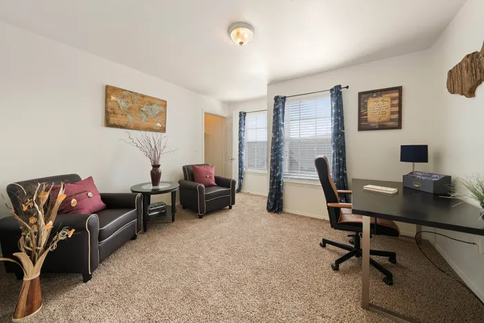 Bright and inviting home office with cozy seating, large windows, and stylish decor for an inspiring work environment.