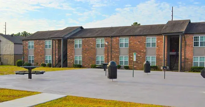 brick apartment building with bbq grills and tables