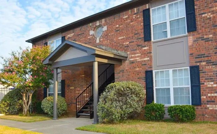 brick apartment building with bushes and grass