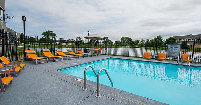 Charming outdoor pool area with vibrant orange loungers and scenic lakeside view, perfect for relaxation and enjoyment.