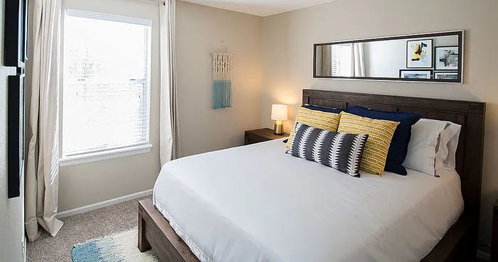 Inviting bedroom with elegant decor, featuring a comfortable wooden bed, bright window, and stylish wall art.