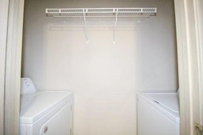 Bright and functional laundry nook featuring a washer, dryer, and convenient overhead shelving.