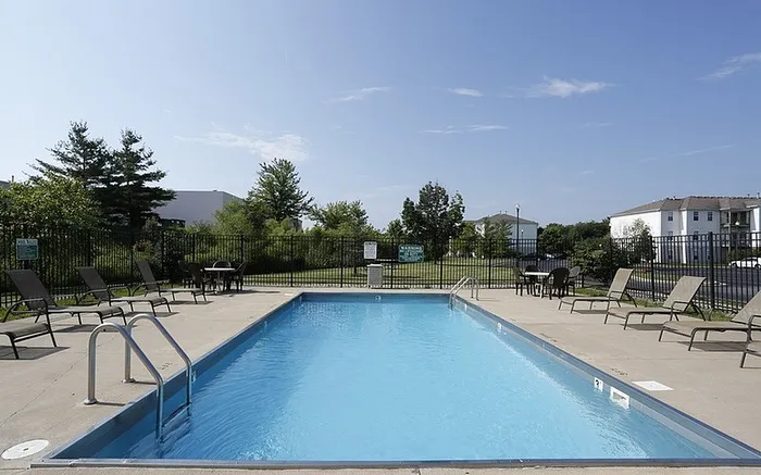 Inviting outdoor swimming pool with lounge chairs and lush greenery at a modern apartment complex.