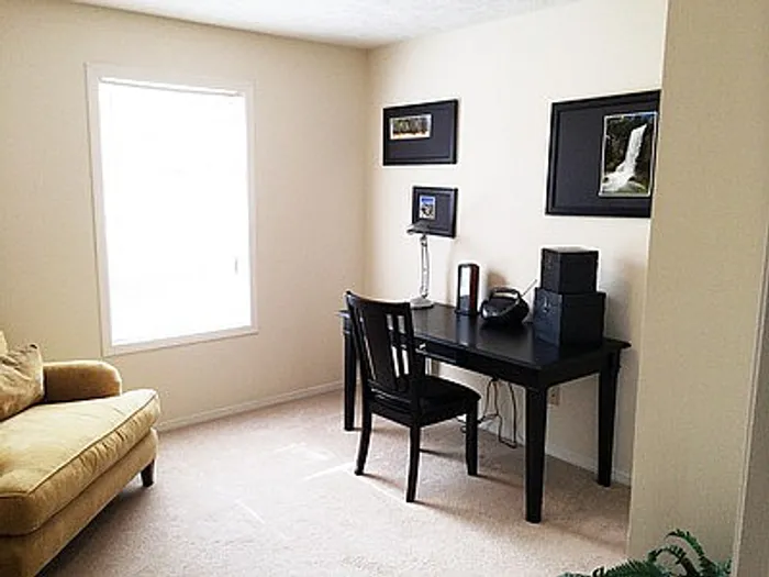 Bright and cozy home office with natural light, featuring a sleek black desk and comfortable seating.