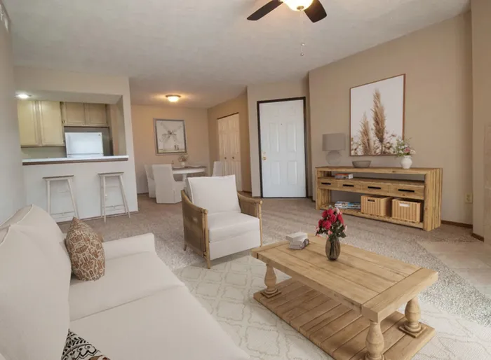 Inviting living room with elegant neutral tones, cozy sofa, polished wooden furniture, and an open-concept kitchen in the background.