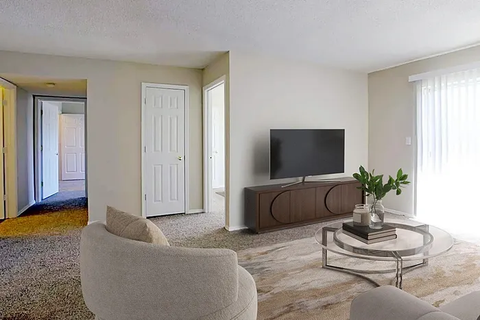 Bright and cozy living room featuring plush carpet, stylish seating, modern TV setup, and inviting natural light through sliding glass doors.