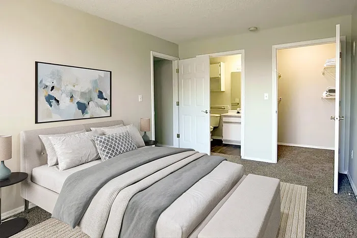 Elegant bedroom with a plush bed, modern artwork, and an en-suite bathroom, offering comfort and style.