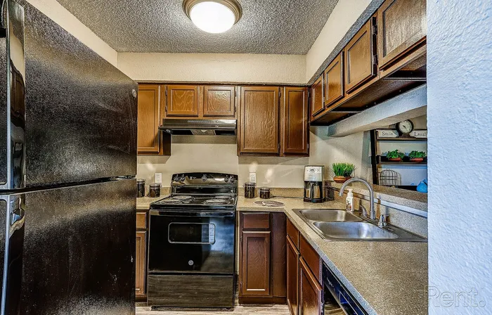 Charming kitchen with sleek black appliances, rich wooden cabinetry, and modern countertops, perfect for culinary adventures.