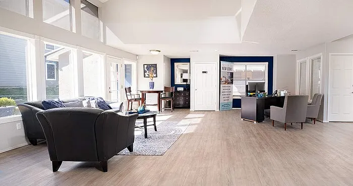 Spacious and bright living area with modern decor, featuring large windows, stylish seating, and elegant hardwood flooring.