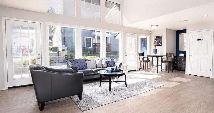 Bright and airy living room with modern furniture, large windows, and elegant decor, offering a welcoming space for relaxation.