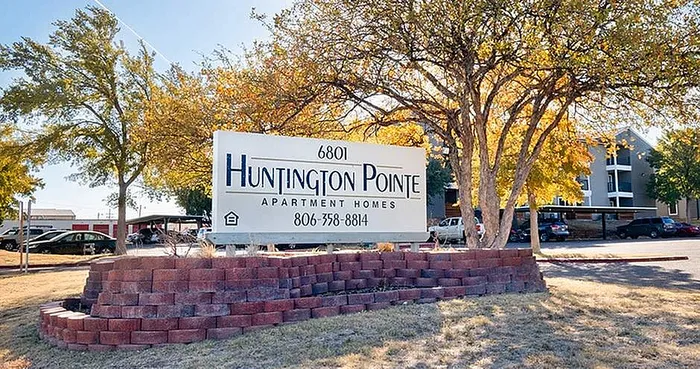 Welcoming entrance sign for Huntington Pointe Apartment Homes surrounded by vibrant autumn trees.