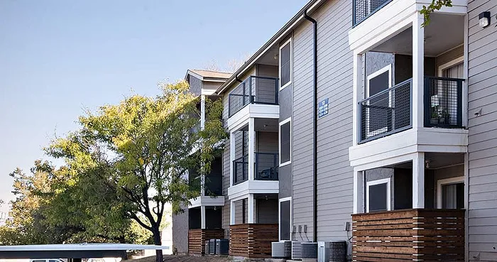 Modern apartment complex with sleek balconies, well-maintained exterior, and lush greenery, offering a welcoming and stylish residential atmosphere.