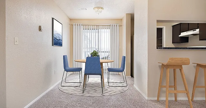 Inviting dining area with natural light featuring a sleek round table, modern blue chairs, and stylish bar stools, perfect for entertaining.