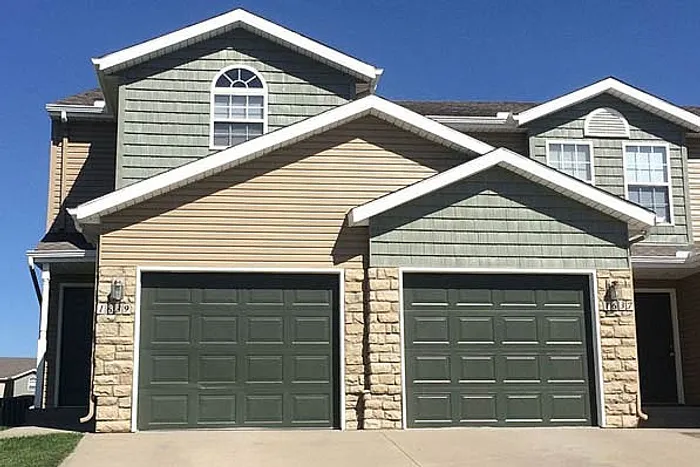 Charming duplex with modern design featuring two spacious garages and elegant stone accents.