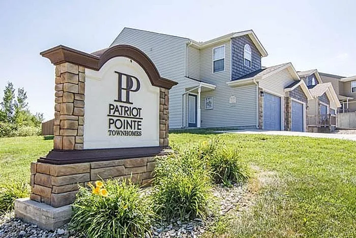 Bright and welcoming exterior view of Patriot Pointe Townhomes with manicured landscaping and modern architectural design.