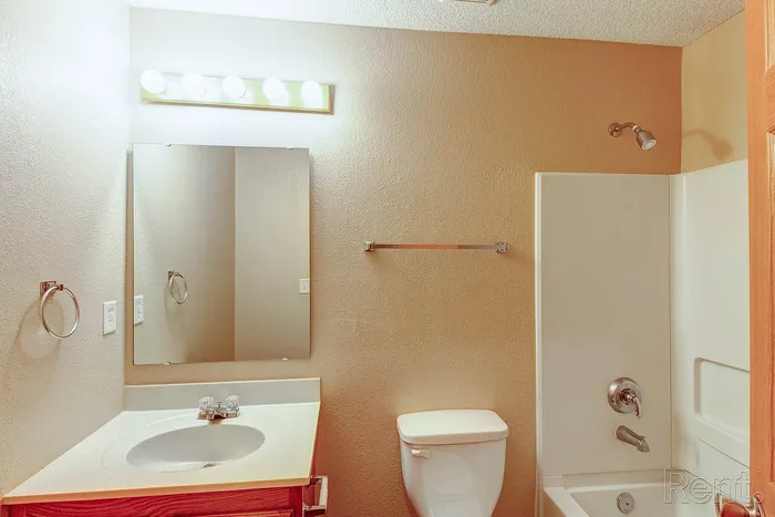 Inviting bathroom with modern lighting, elegant mirror, and pristine fixtures. Perfect blend of style and functionality.