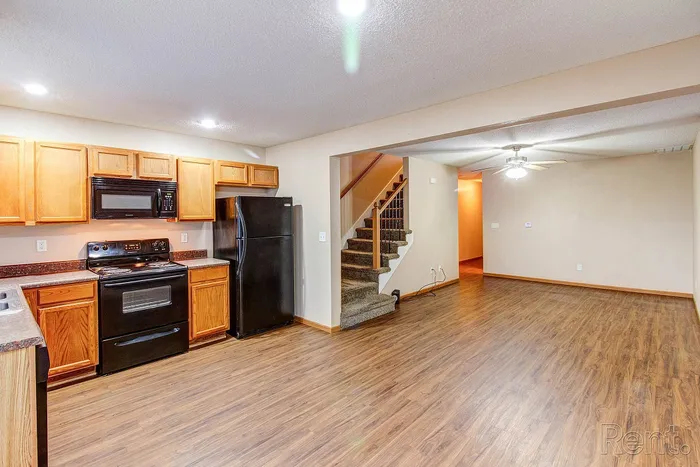 Inviting open-concept kitchen and living area with warm wood floors, modern appliances, and cozy staircase.