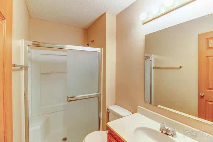 Bright and inviting bathroom featuring a frosted glass shower, sleek vanity, and modern lighting.