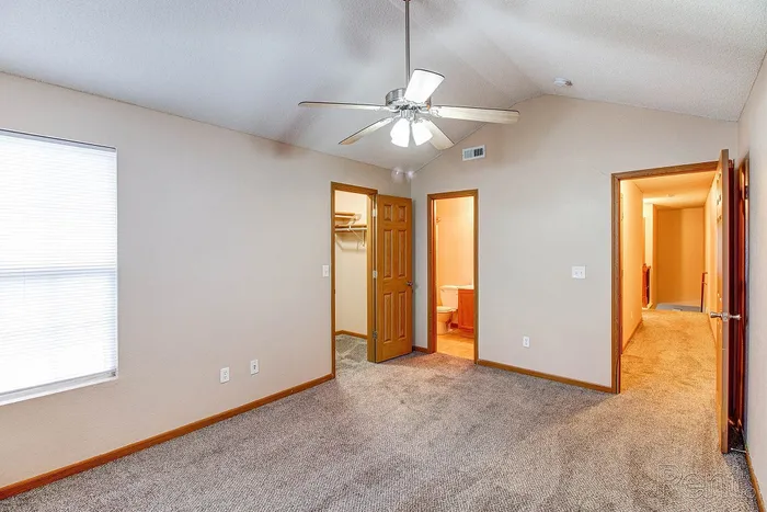 Inviting bedroom with plush carpet, featuring a ceiling fan, closet, and attached bathroom for ultimate comfort.