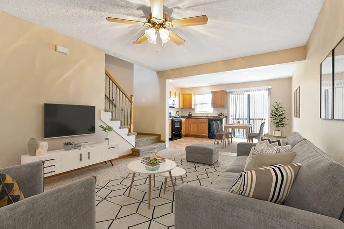 Inviting open-concept living area with elegant gray sofas, modern decor, and a cozy dining space leading to a bright, airy kitchen.
