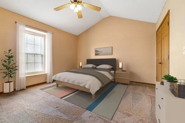 Inviting bedroom with a cozy bed, stylish decor, and warm, earthy tones highlighted by natural light from a large window.