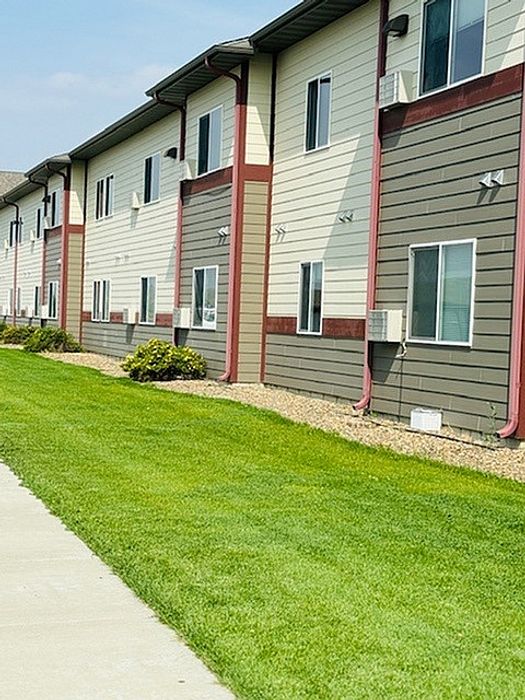 Charming apartment exterior with modern siding, manicured lawn, and a tranquil setting, perfect for comfortable living.