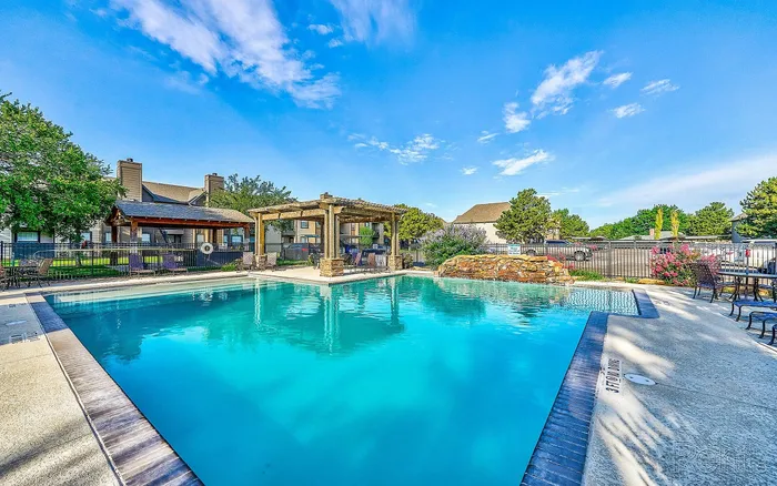Inviting outdoor pool area with vibrant greenery and spacious seating, perfect for relaxation and leisure.