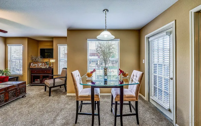 Charming dining area with a glass table set for two, highlighted by soft light and surrounded by warm decor in a cozy apartment.