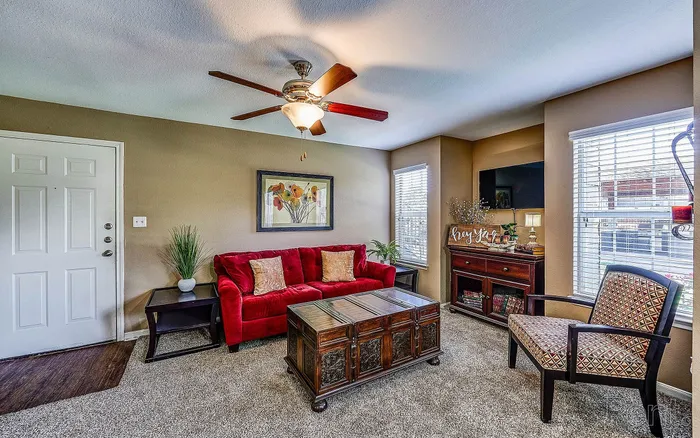 Inviting living room showcasing a vibrant red sofa, elegant wooden coffee table, and stylish armchair, complemented by abundant natural light and tasteful decor.