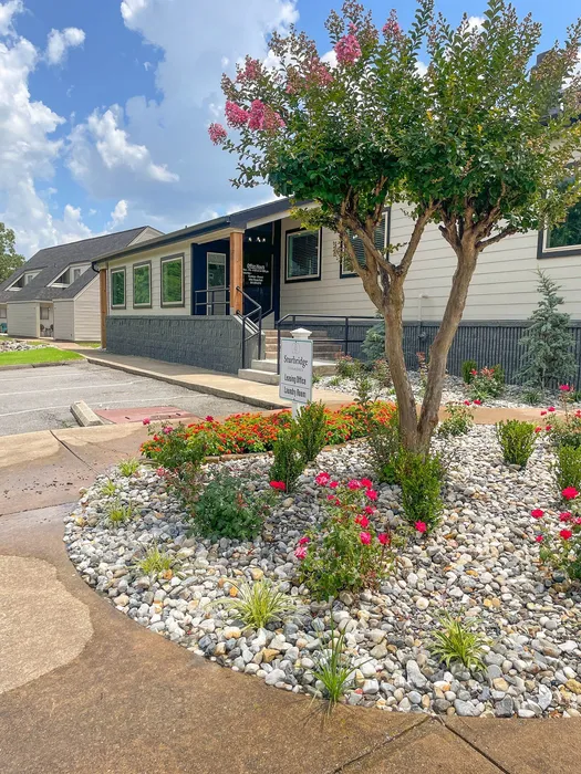 Charming apartment leasing office surrounded by vibrant landscaping and colorful flowers, offering a welcoming atmosphere.