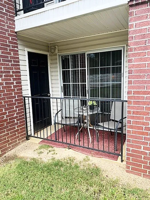Cozy apartment patio area with two chairs and a table, surrounded by charming brickwork and greenery, perfect for relaxation.